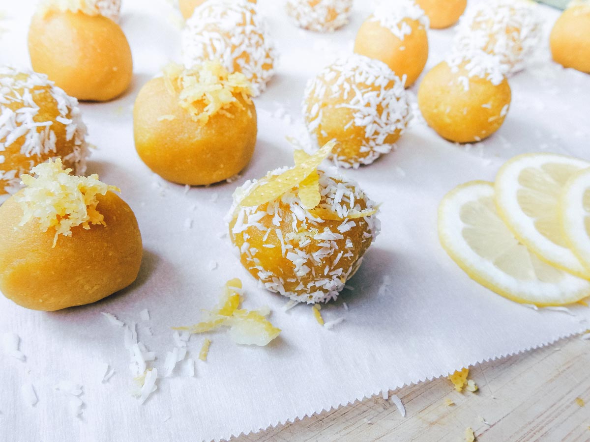 Pot of gold lemon turmeric bliss balls on parchment paper and wooden cutting board.